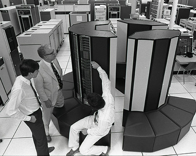 Three people standing around a super computer