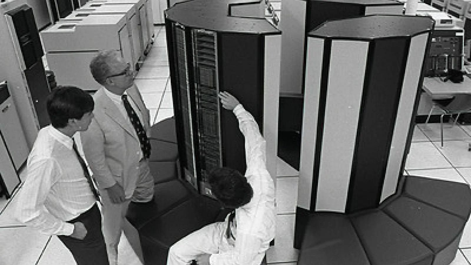 Three people standing around a super computer