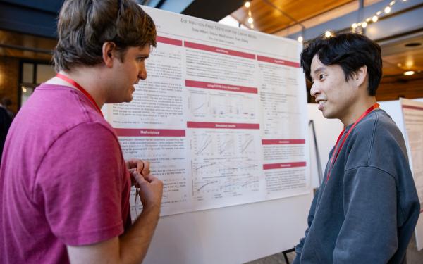 Two students standing in front of a poster discussing their research