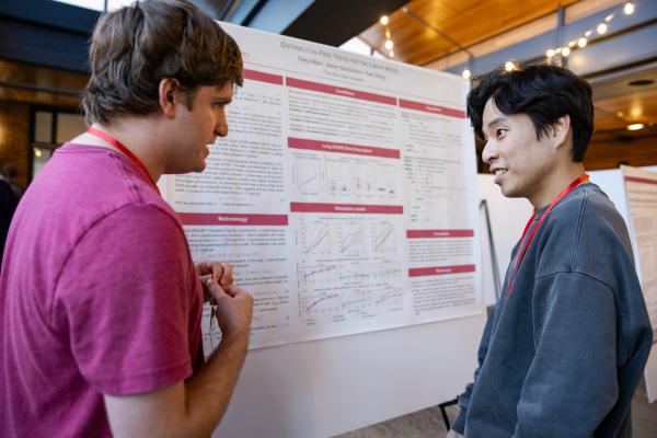 Two students standing in front of a poster discussing their research