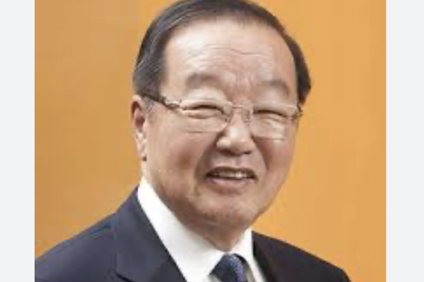 Young-Jack Lee smiling in a suit in front of an orange backdrop