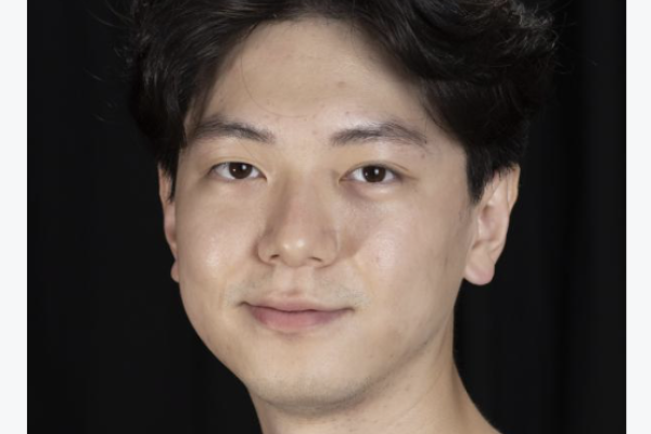 Jae Ho in a gray shirt in front of a black back drop