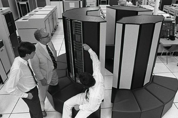 Three people standing around a super computer