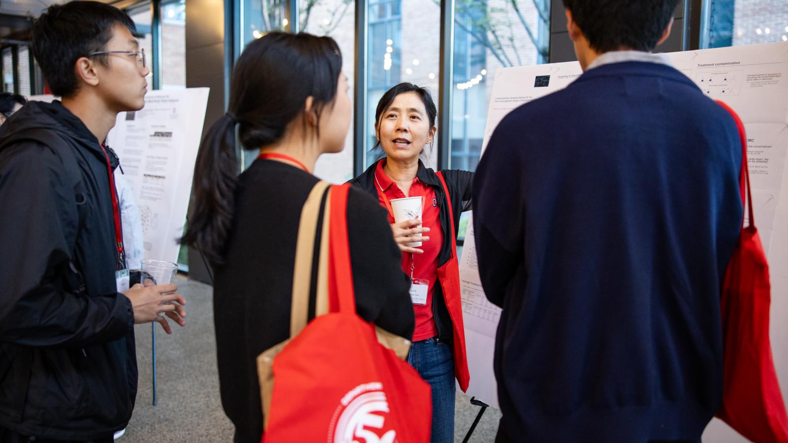 A researcher presenting their poster to graduate students