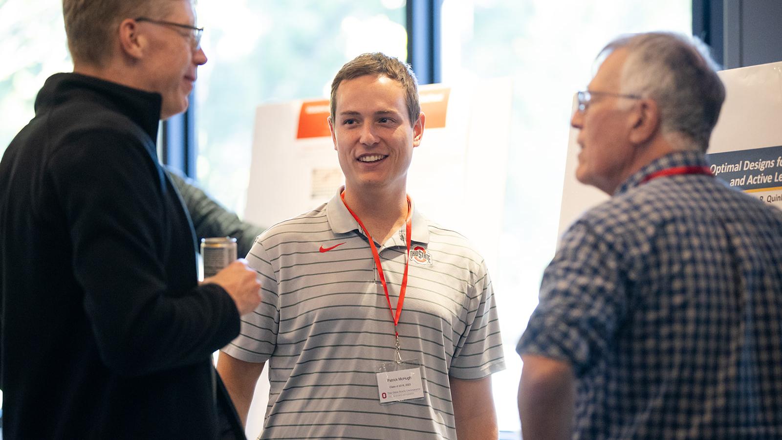 a graduate student talking with an alumnus and faculty member