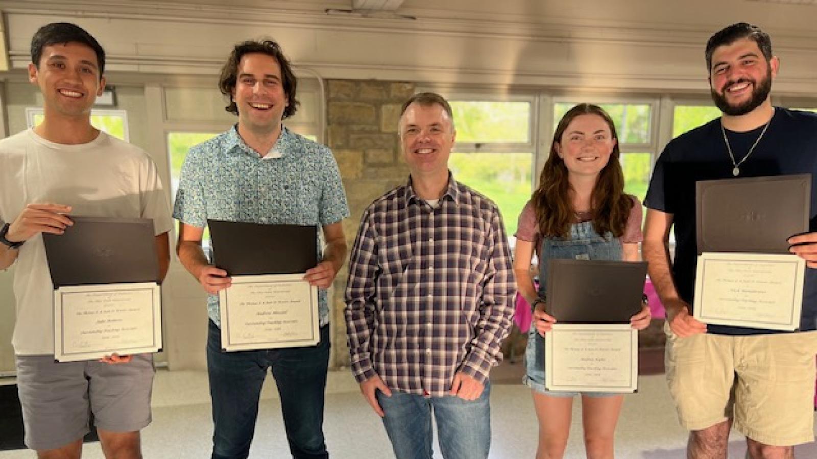 Powers TA Award Recipients Jacob Roberts, Andrew Heeszel, Andrea Kuhn, and Nicholas Mandarano standing with Christopher Hans and holding certificates
